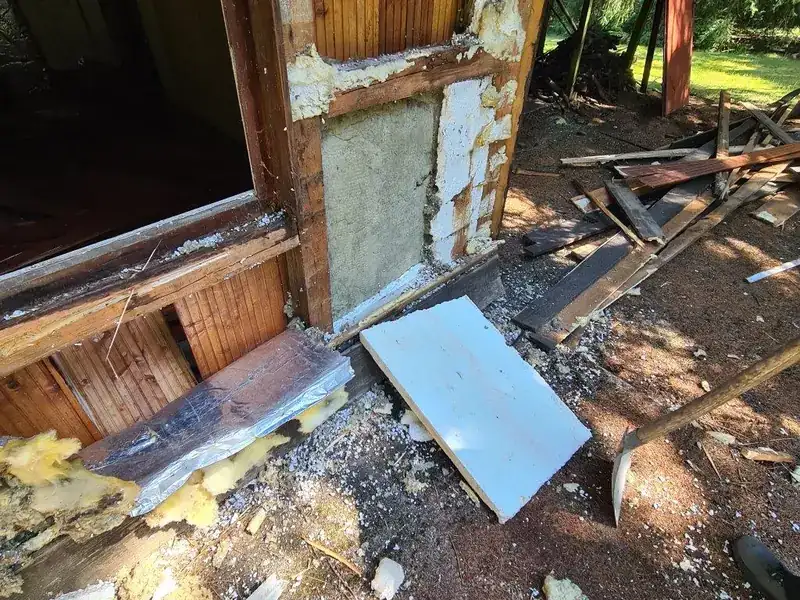 Geöffnete Wand eines Gartenhauses mit herausgelöster Dämmung beim Rückbau